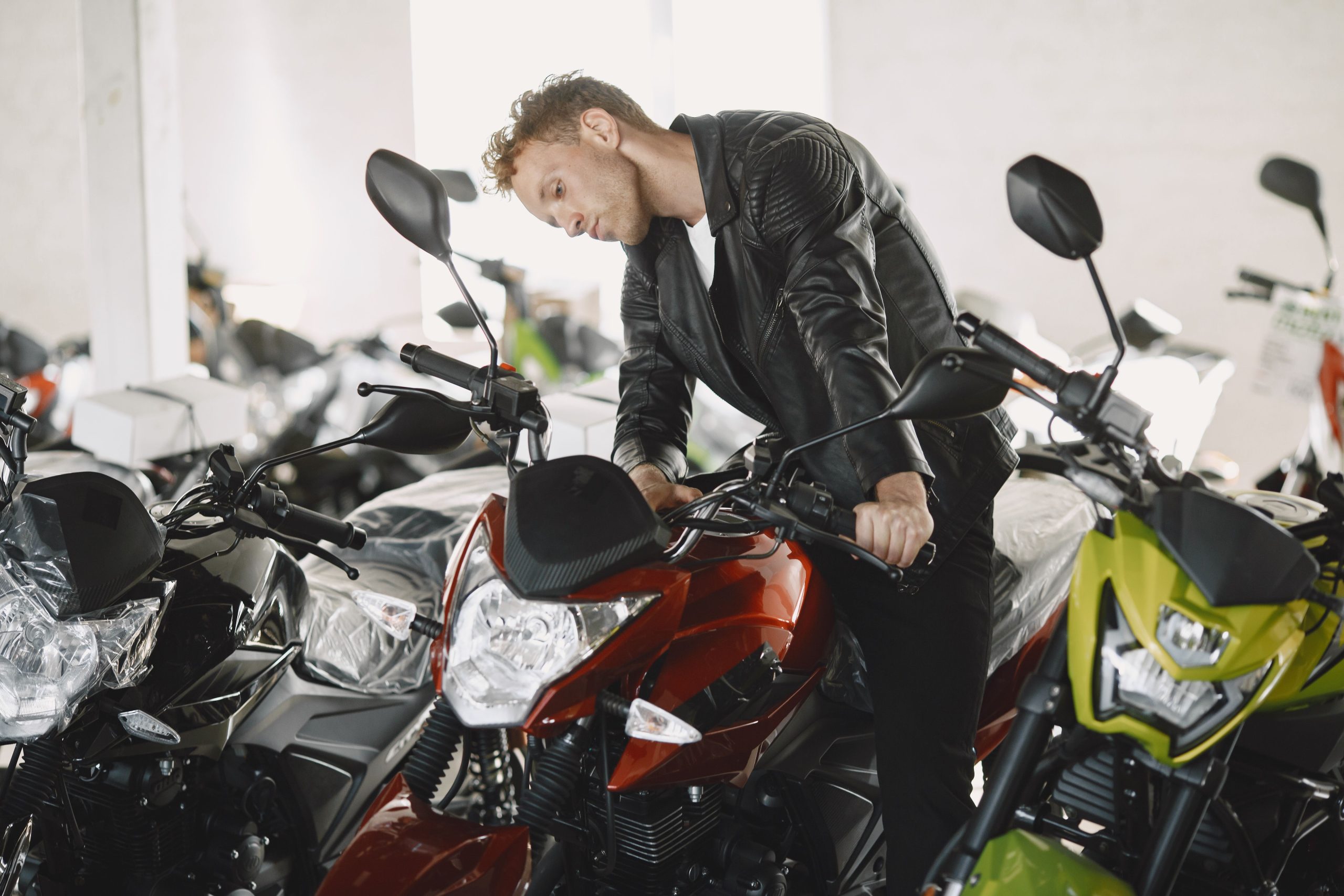 Homme en blouson cuir inspectant motos concession