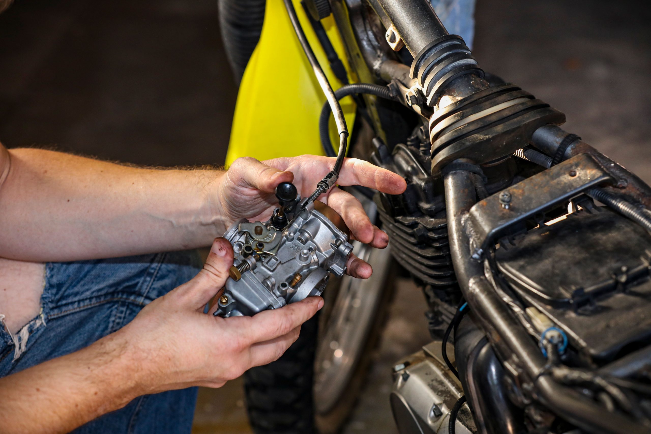 Mains mécanicien réparant carburateur moto