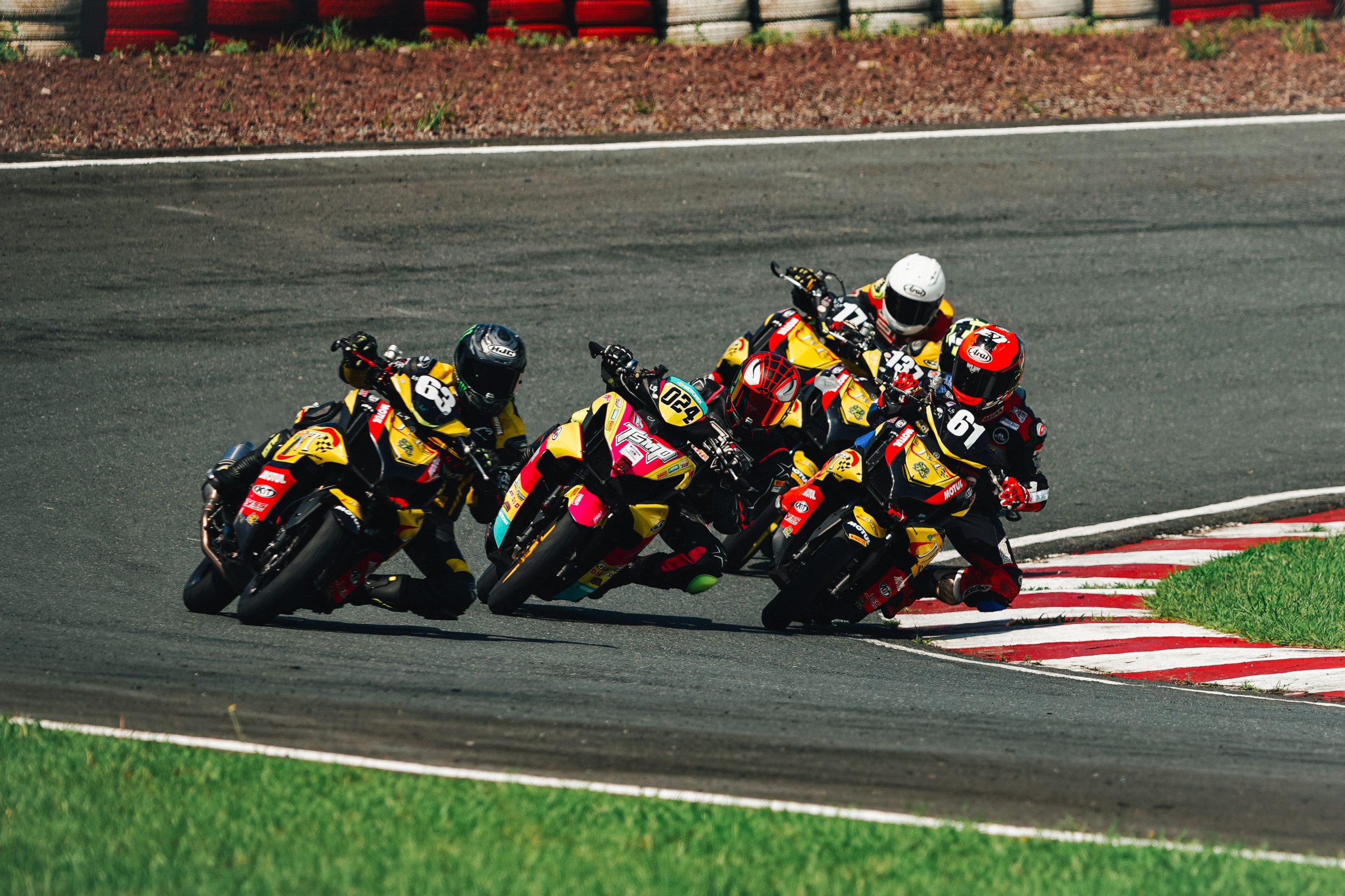 Quatre motocyclistes en compétition sur piste courbe
