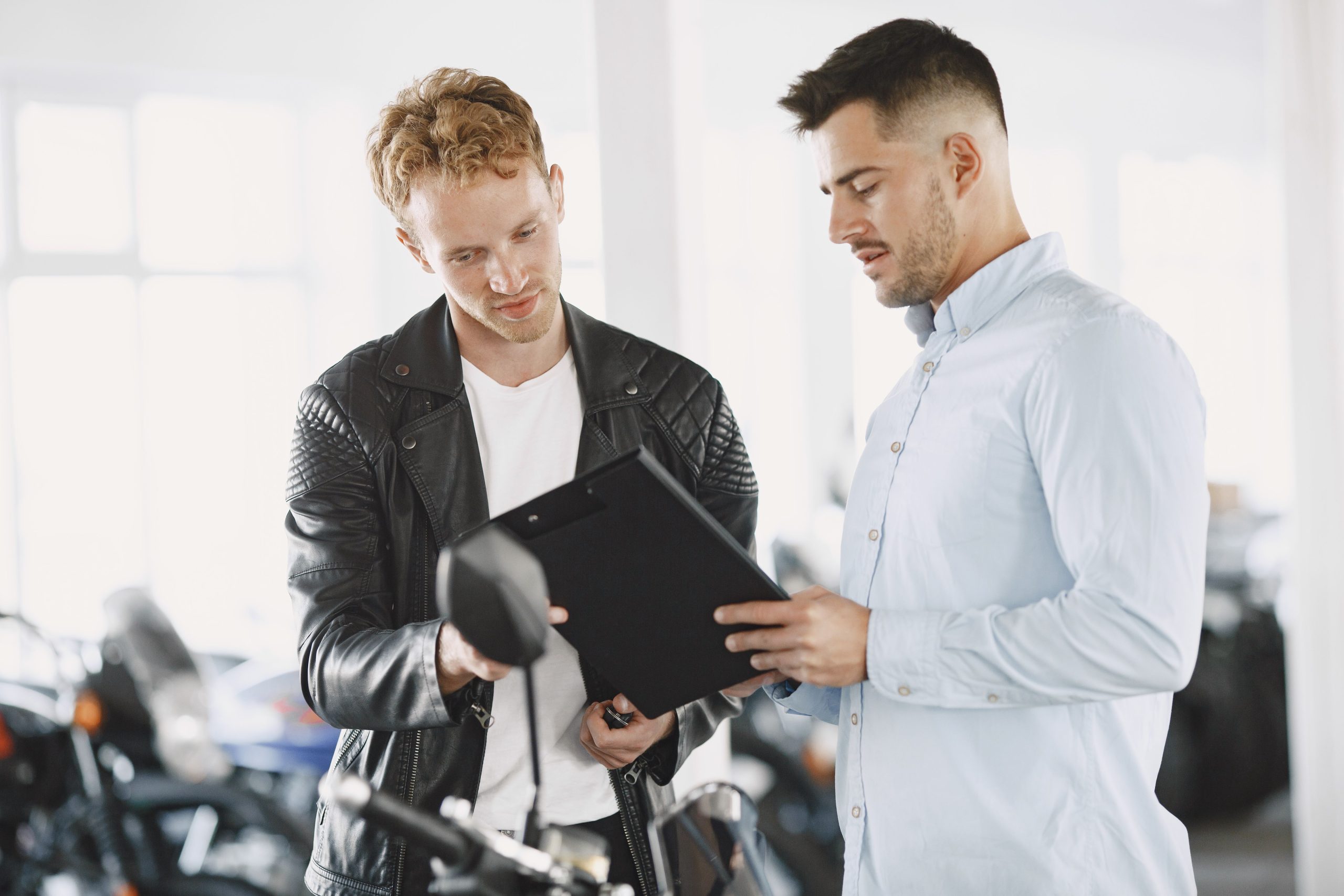Deux hommes discutent contrat chez concessionnaire moto