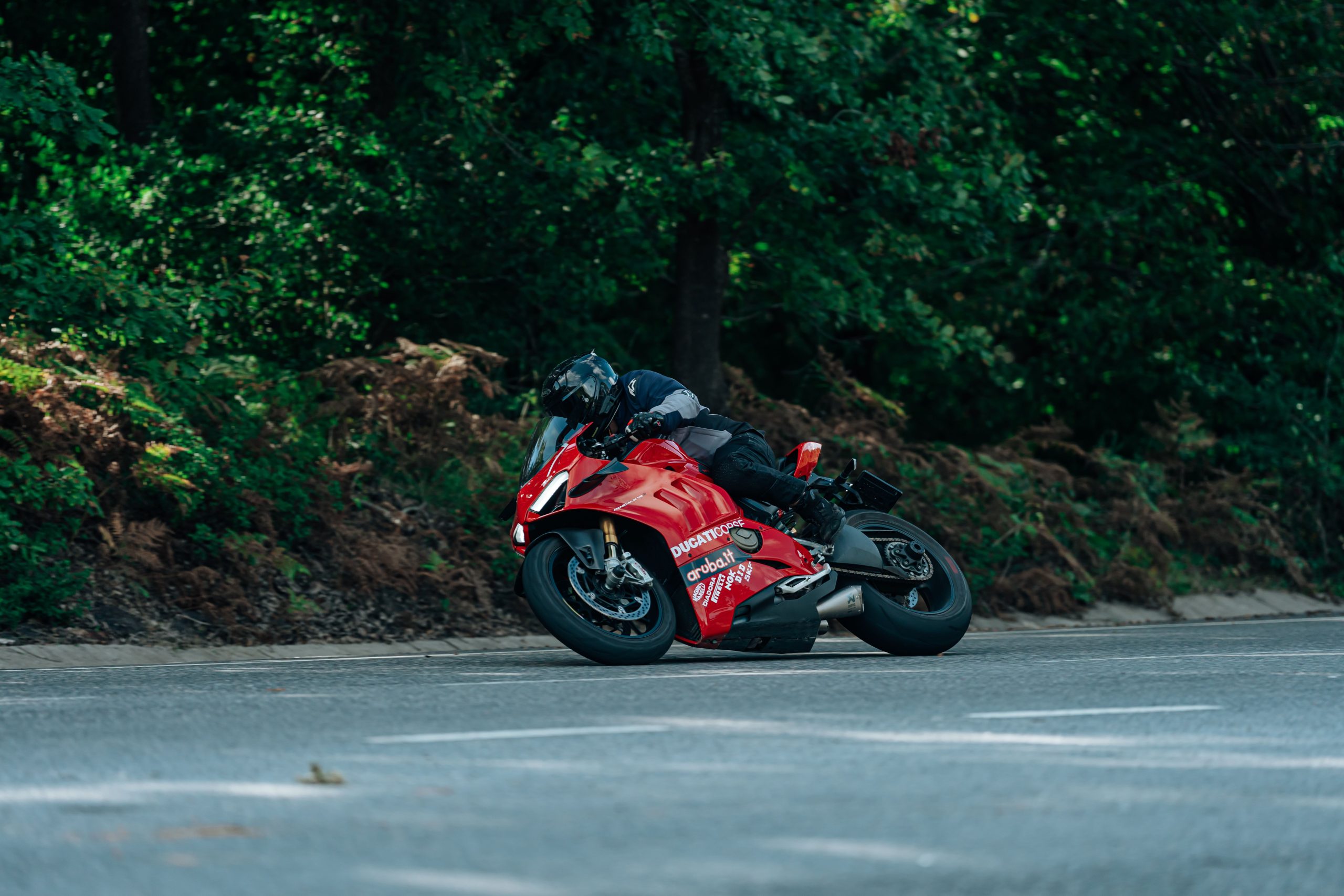 Ducati rouge penchée dans un virage forestier compétitif